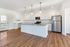 Modern kitchen with sleek granite countertops, stainless steel appliances, and elegant pendant lighting over a large island, complemented by rich wooden flooring.