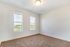 Bright, airy bedroom with plush carpeting and scenic views through two large windows.