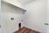 Bright and spacious laundry room with sleek white walls and warm wooden flooring, ready for washer and dryer installation.