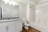Modern bathroom with sleek granite countertops, elegant white cabinetry, and a pristine bathtub, ideal for a luxurious home.