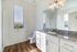Bright and modern bathroom featuring elegant granite countertops, pristine white cabinetry, and warm wood flooring.