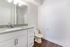 Elegant bathroom featuring a modern granite countertop, sleek white cabinets, and a contemporary light fixture.