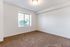 Bright, spacious bedroom with plush carpeting and a large window offering abundant natural light.