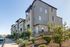 Modern apartment complex with contemporary architecture and lush landscaping under a clear blue sky.