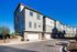 Charming row of modern three-story townhouses with large windows and attached garages, set against a clear blue sky.