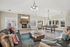 Contemporary living room with stylish leather sofas, vibrant cushions, a cozy stone fireplace, and an elegant chandelier. The room features a sleek pool table, large windows for natural light, and a modern rustic coffee table.