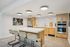 Modern kitchen design with a sleek island, bar seating, stainless steel appliances, and elegant recessed lighting.