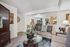 Elegant living room showcasing a modern interior design with plush seating, glass coffee table, and decorative accents, leading into a stylish dining area.