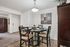 Elegant dining area with contemporary round table set for four, under a stylish light fixture, showcasing modern design and cozy ambiance.