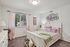 Ogden, UT, Pet-Friendly Apartments - Pinebrook Apartments - Bedroom With White Bed Frame, Patterned Bedding, Large Window With Pink Curtains, Carpet, And Decorative Wall Art.