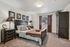 Elegant bedroom featuring a luxurious bed with plush pillows, dark wood furniture, and decorative wall art, creating a cozy and inviting atmosphere.