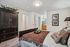 Charming bedroom with elegant dark wood wardrobe, cozy bed with decorative pillows, and ensuite bathroom access, perfect for relaxation.