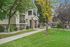 Charming apartment exterior with a lush green lawn, mature trees, and a welcoming balcony, perfect for enjoying outdoor relaxation.