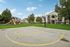 Vibrant apartment community featuring modern buildings, a playground for children, and a basketball court, set against a backdrop of lush green lawns and clear blue skies.