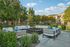 Inviting apartment complex courtyard with modern outdoor seating, lush greenery, and a sunny ambiance.