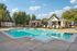 Inviting outdoor pool with elegant lounge chairs, surrounded by lush trees and charming brick architecture, perfect for relaxation.