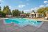 Inviting community pool area surrounded by lush trees and cozy lounging chairs, perfect for relaxation and leisure.