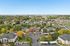 Aerial view of a picturesque residential community with tree-lined streets, beautifully landscaped gardens, and modern apartment buildings, offering a serene and vibrant living environment.