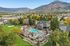 Scenic aerial view of a vibrant apartment complex with a sparkling pool, lush green landscaping, and majestic mountain backdrop, offering a perfect blend of relaxation and outdoor beauty.