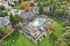 Stunning aerial view of a vibrant apartment complex with a central pool, lush greenery, and cozy seating areas surrounded by trees in a serene neighborhood.