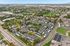 Vibrant aerial view of a modern apartment complex surrounded by lush greenery, showcasing a scenic blend of urban development and natural beauty.
