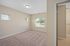 Bright and inviting bedroom with soft carpet flooring, neutral walls, and ample natural light from large windows overlooking a serene outdoor view.