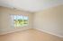 Bright and airy room with large window showcasing lush green views, featuring stylish wooden flooring and neutral walls, perfect for personalization.