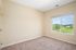 Bright and inviting room with plush carpet, large window offering serene green views, and neutral walls perfect for personal touches.