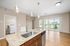 Modern apartment interior boasting sleek granite countertops, stainless steel sink, and hardwood floors with ample natural light from large sliding doors.