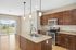 Bright and modern kitchen with granite countertops, stainless steel appliances, and elegant pendant lighting, featuring an inviting open layout with large sliding glass doors leading to a green view.