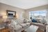 Bright and inviting living room with elegant beige sofas, stylish decor, and a large window offering stunning views of the neighborhood.