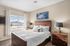 Bright and cozy bedroom with wooden furnishings, featuring a large window with scenic views and elegant decor.