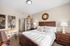 Elegant bedroom with rustic wooden furniture, world map decor, plush bedding, and natural light, offering a cozy and inviting ambiance.