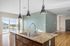 Open-concept kitchen with granite countertops and modern pendant lighting, complemented by spacious living area and large windows for natural light.