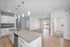 Modern open-plan apartment with a sleek kitchen, featuring an island and pendant lighting, leading to a bright living area and private balcony access.