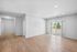 Spacious modern living room with elegant wood flooring, large windows, and natural light, creating a bright and inviting space.