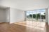 Bright and spacious empty room with floor-to-ceiling windows, offering abundant natural light and picturesque views of greenery, perfect for modern living.