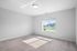 Bright and airy carpeted room with a large window offering scenic outdoor views, perfect for a cozy bedroom retreat.