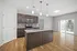 Modern kitchen with sleek granite island, stainless steel appliances, and elegant pendant lighting, opening to a bright living area with hardwood floors and large sliding glass doors.