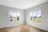 Bright corner room with large windows offering serene outdoor views and beautiful hardwood floors.