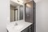 Contemporary bathroom with sleek dark wood cabinetry, large mirror, and elegant modern fixtures.