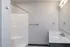 Modern bathroom with sleek white shower, elegant vanity, and a large mirror adds sophistication and style.