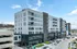 Modern apartment building with sleek design, featuring large windows and private balconies, offering vibrant urban living with convenient parking.