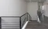 Modern hallway with sleek railing and contemporary flooring leads to spacious rooms, offering a stylish and inviting atmosphere.