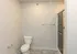Modern bathroom with sleek tiled flooring, pristine toilet, and glass-enclosed shower.
