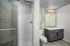 Elegant modern bathroom with sleek glass shower, large mirror, and stylish gray vanity.