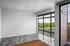Bright, modern living space with large floor-to-ceiling windows offering picturesque views of lush greenery and a charming neighborhood street.