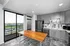 Modern kitchen with sleek gray cabinetry, a black fridge, stylish tile backsplash, and a wooden island, complemented by large windows offering scenic views.