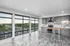 Modern apartment kitchen with sleek gray cabinetry, stainless steel appliances, and expansive windows offering stunning city views.