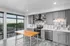 Modern kitchen with sleek gray cabinetry, stainless steel appliances, and a bright open view of the cityscape through large windows.